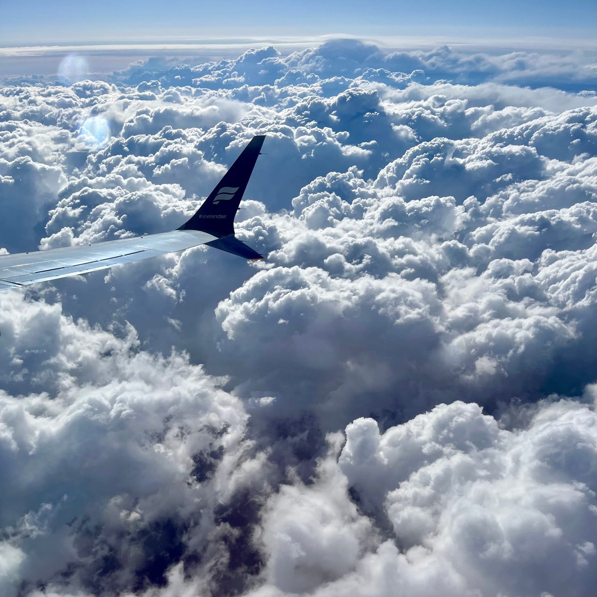 Plane wingtip over fluffy clouds