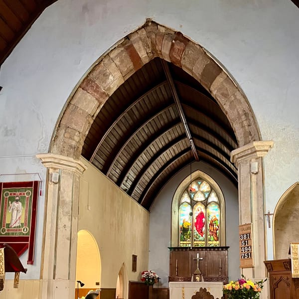 Stained glass window and altar at the front of a church.